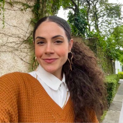 Anna Chaves sorrindo em meio a uma obra, segurando amostras de tecido